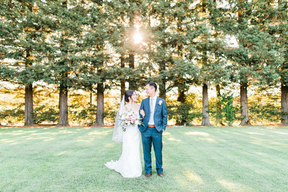 Newlyweds pose in front of a woodsy backdrop during golden hour